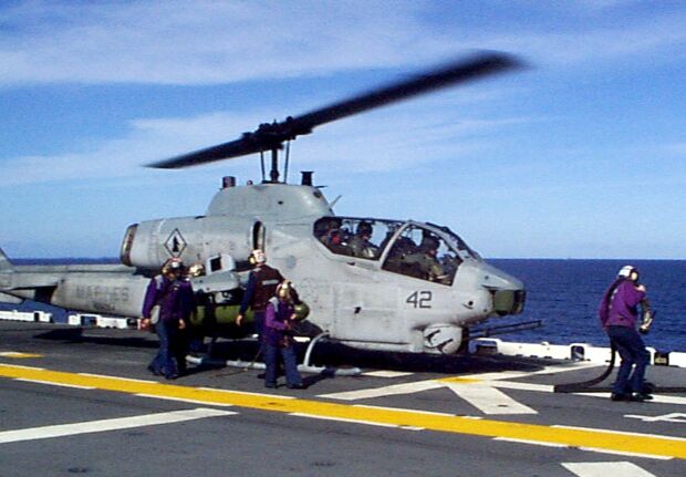 Image: Flight deck crew members aboard the USS Wasp hot refuel an AH-1W Super Cobra.