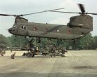 Image: Soldiers sling load a howitzer below a CH-47 Chinook.