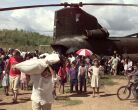 Image: A man in Casamacoa, Honduras, carries a sack of corn away from a U.S. Army CH-47 Chinook.