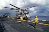 Image: A Navy Landing Signal Enlisted signals a CH-53 Super Stallion helicopter to lift off.